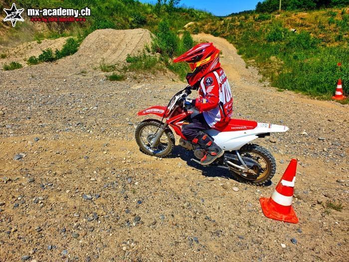 Enfant sur une petite moto de motocross Honda passant à côté d’un cône