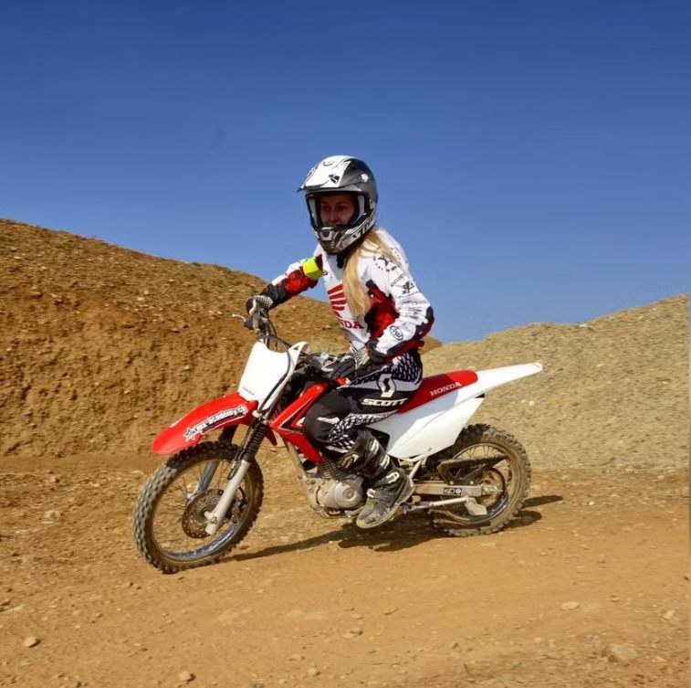 Frau auf einem kleinen roten Motocross-Bike auf der Strecke