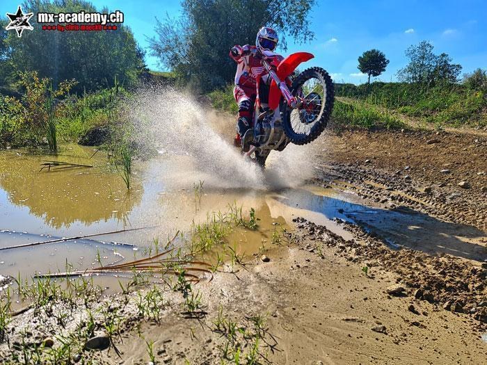 Enduro-Fahrer durchquert einen Bach, das Wasser spritzt