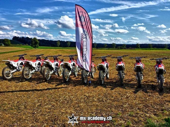 Rote Honda Motocross-Mietbikes in einer Reihe neben der MX-Academy-Fahne