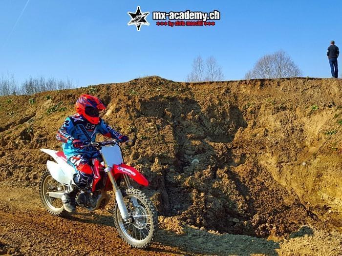 Jugendlicher auf dem Motocross-Bike vor einer Erdwand