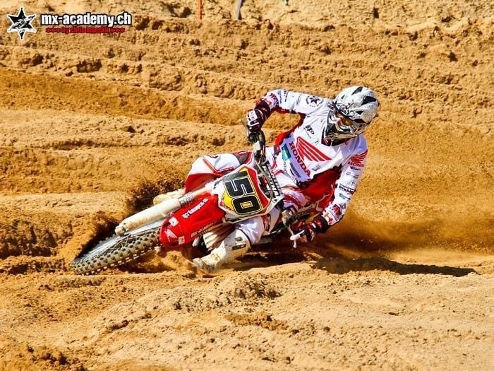Motocross-Fahrer mit Startnummer 50 legt sich in eine Sandkurve